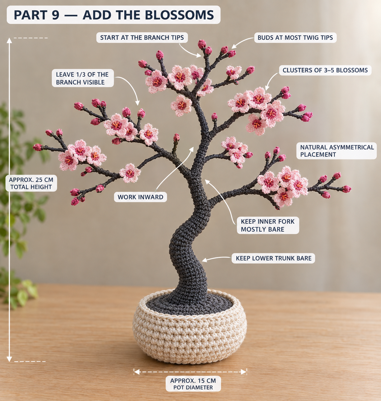 The finished crochet bonsai with blossom clusters and buds at the branch tips, the lower trunk and inner fork left bare, about 25 cm tall in a 15 cm cream pot
